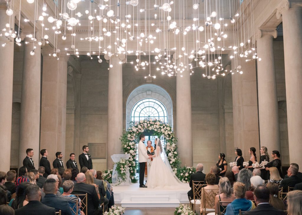 A bride and groom exchange wedding vows inside the grand entrance of the Baltimore Museum of Art