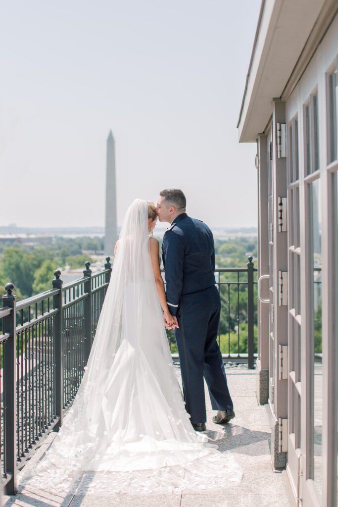a newly married couple pauses for a kiss at the Hay Adams Hotel overlooking the washington monument